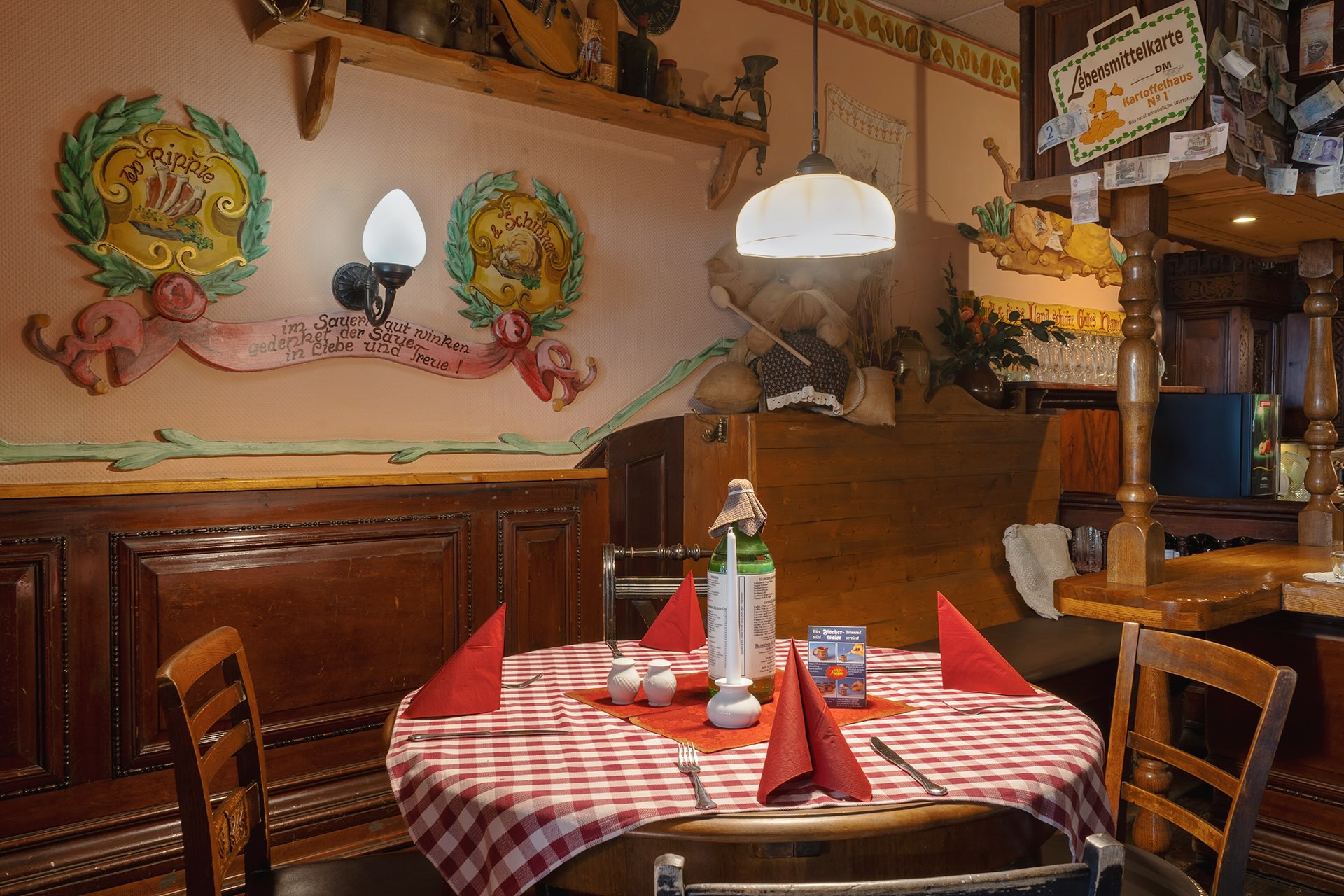 Gedeckter Tisch mit rot-karierter Tischdecke und rustikaler Wanddekoration